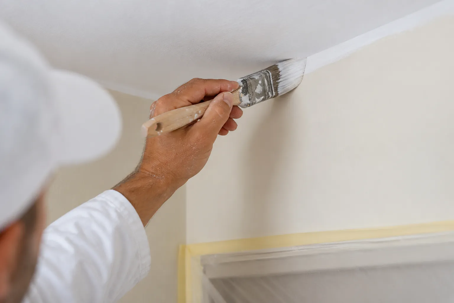 Pintar piso en Elche: una brocha recortando la línea entre la pared y el techo con un acabado limpio